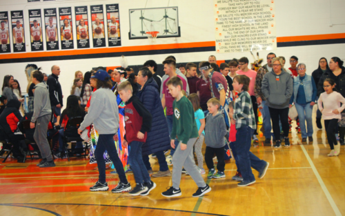 A group of children walking in a gymnasium.