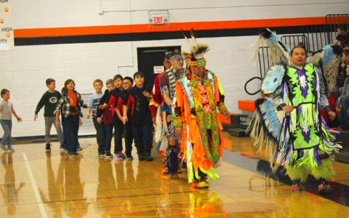 Group of people in Native American costumes at cultural event.