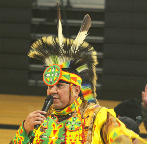 A man wearing a headdress holds a microphone.