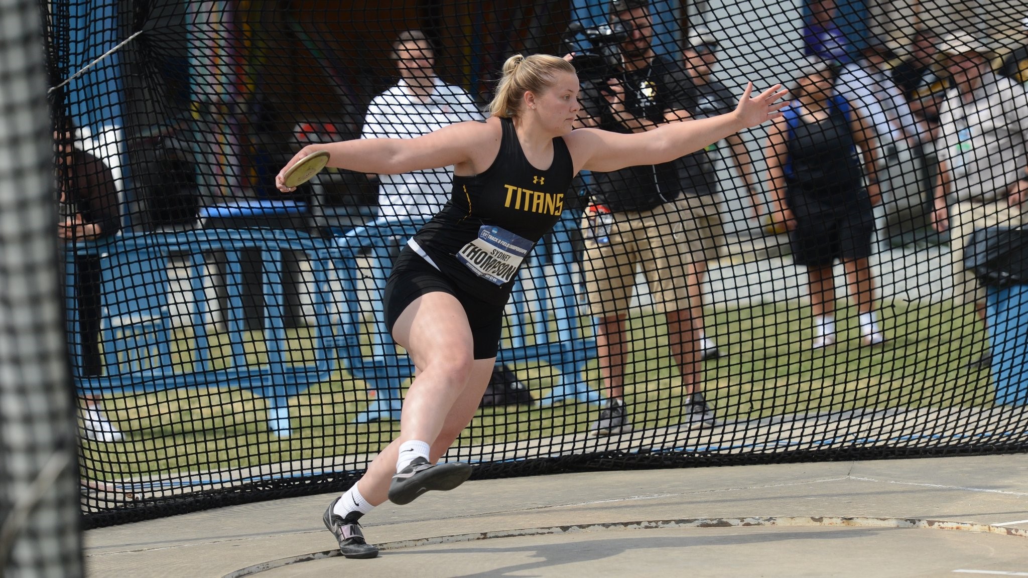 A female athlete competes in a track and field event, throwing a discus with strength and precision.