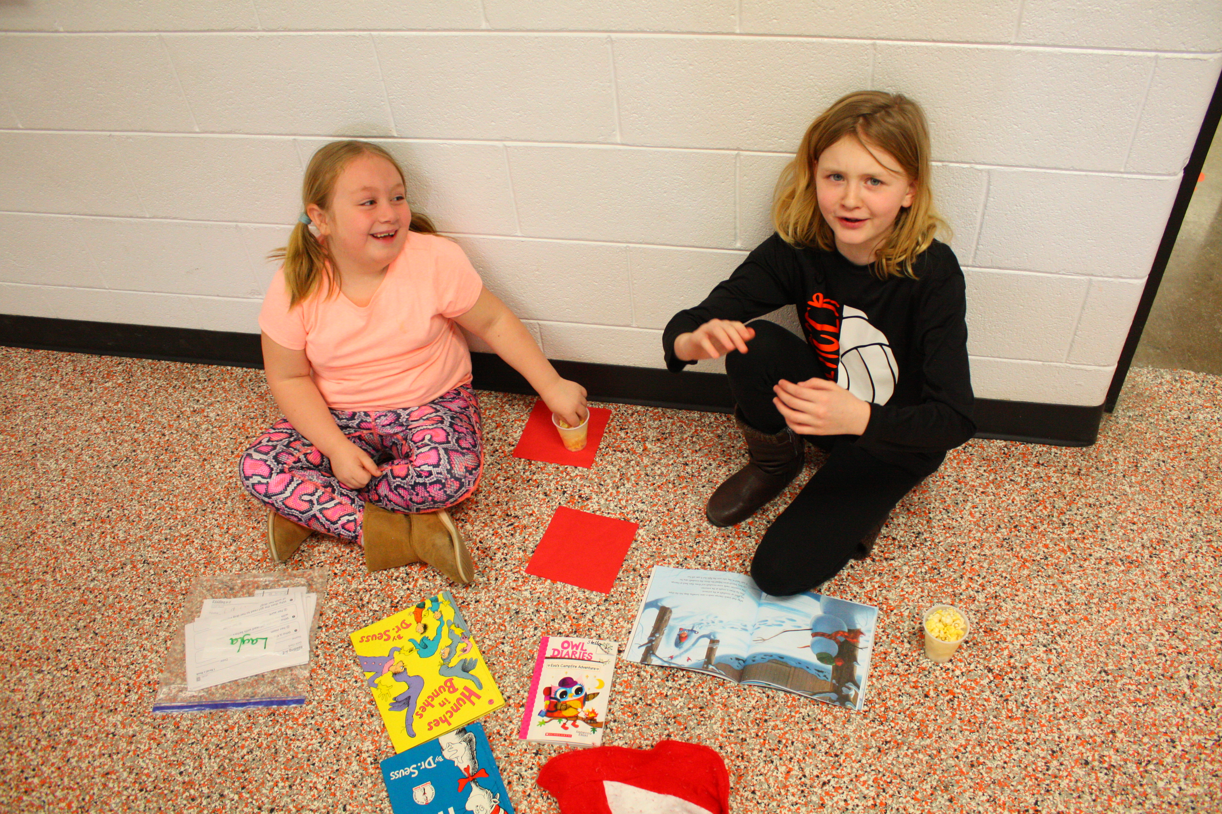 Two girls sitting on the floor, engrossed in books.