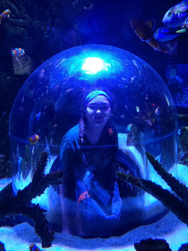 A child happily sitting in a bubble inside an aquarium