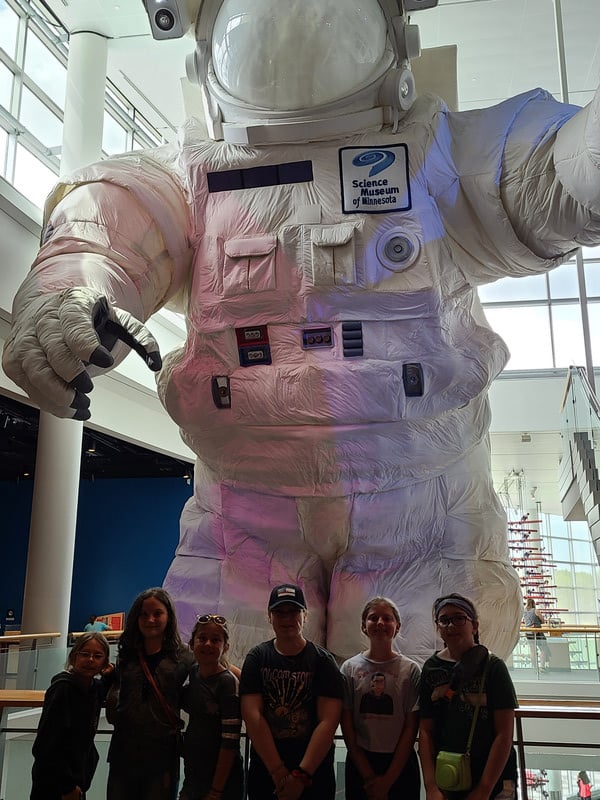 A group of people standing in front of a giant astronaut