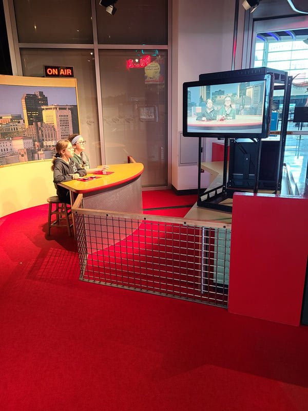 Two people sitting at a desk watching TV.