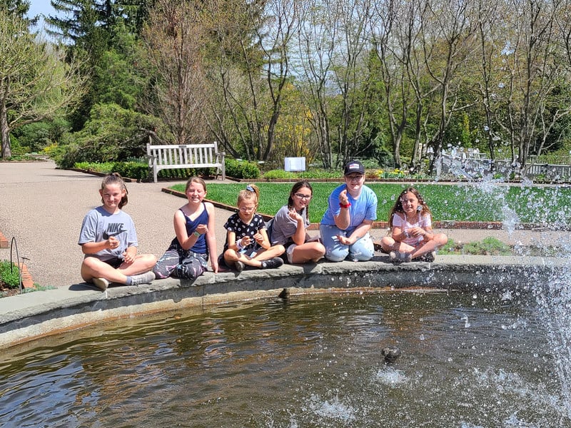 Friends relaxing on stone ledge by fountain.