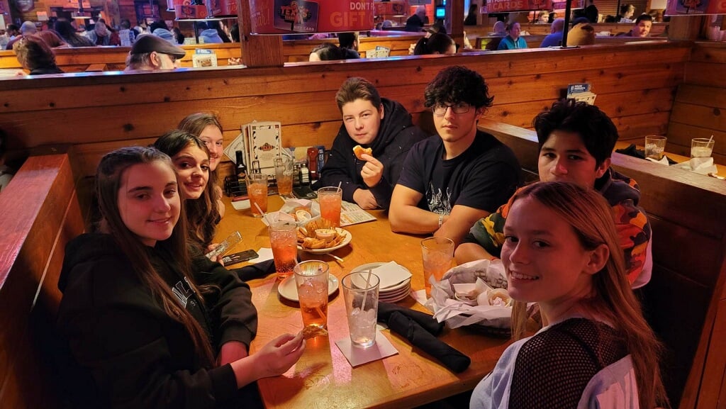 A group of individuals sitting around a table, socializing at a restaurant.