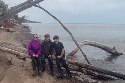 A group of people sitting on top of a beach next to a fallen tree