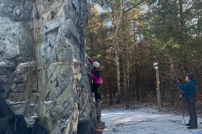 A man and a woman climbing up the side of a mountain