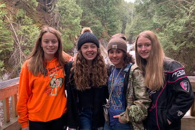 A group of young women standing next to each other on a bridge