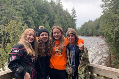 A group of young women standing next to each other on a bridge