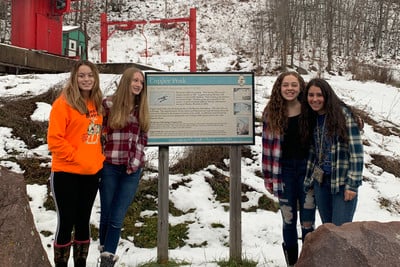 A group of young women standing next to a sign