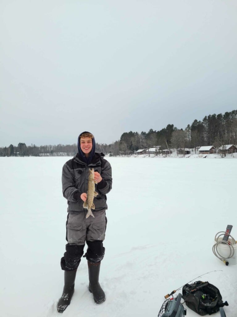 A man holding a fish on a frozen lake.