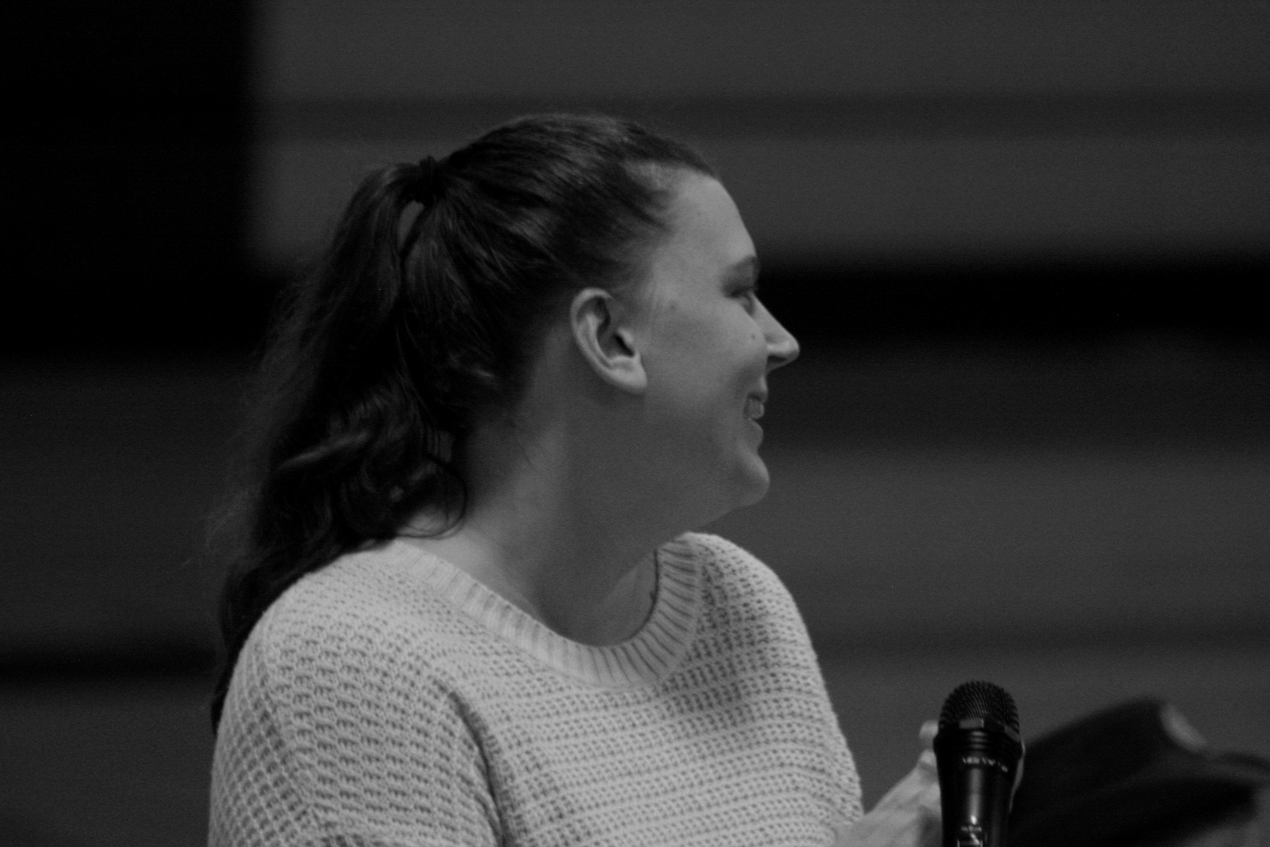 A woman in a white sweater holding a microphone