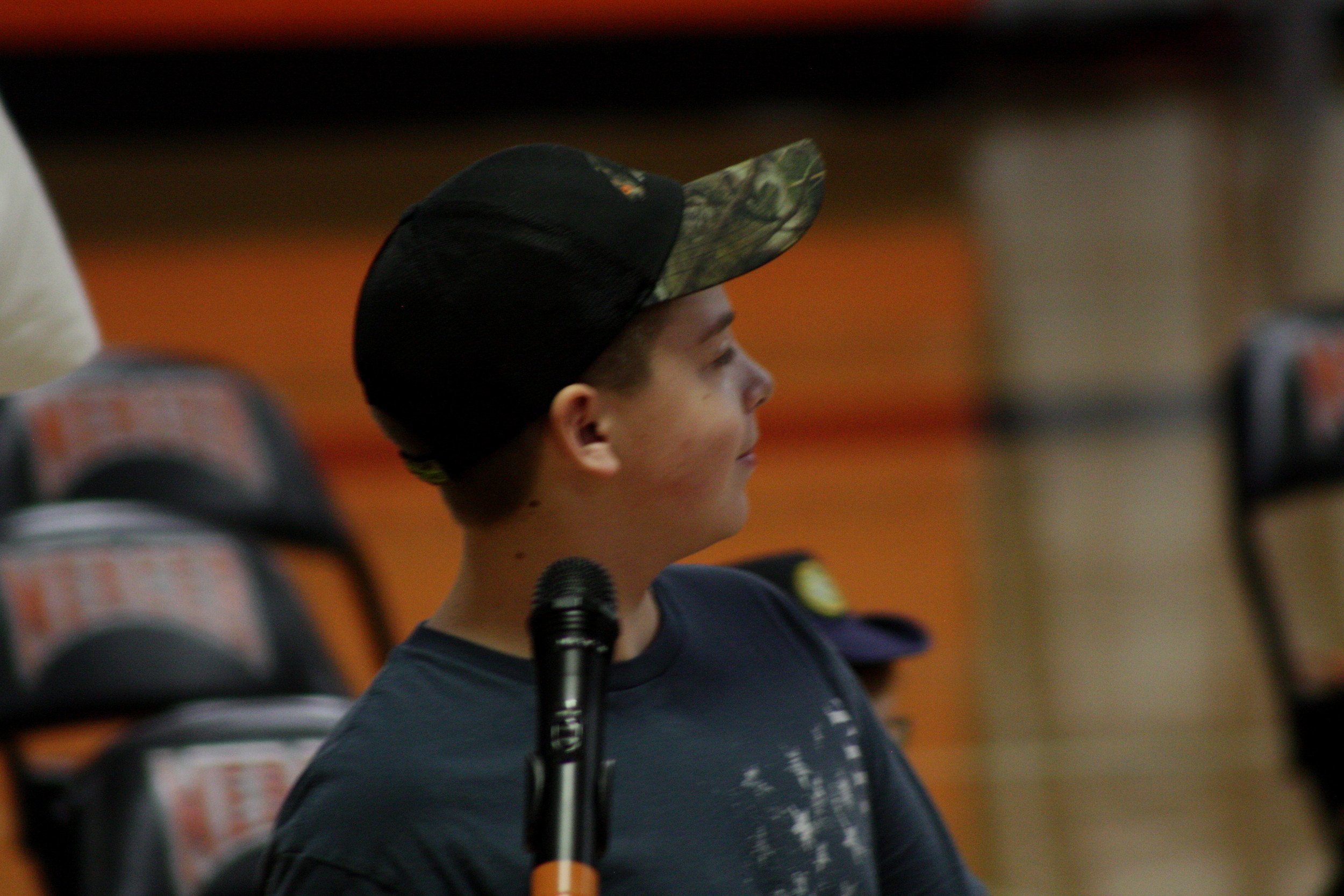 A young boy wearing a hat and holding a microphone