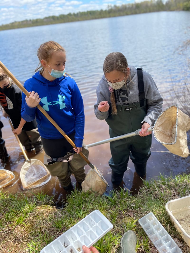 Two girls happily hold nets in the water