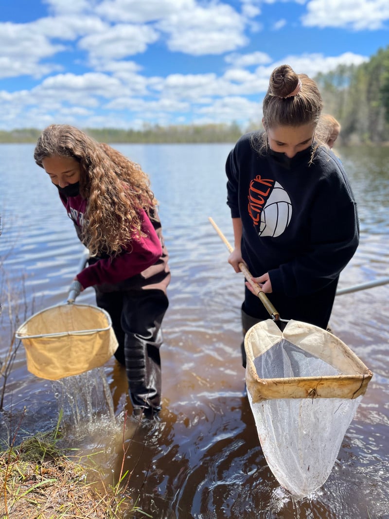 Two girls happily hold nets in the water