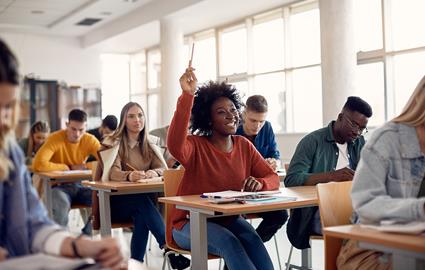 Smiling child raising their hand in a classroom