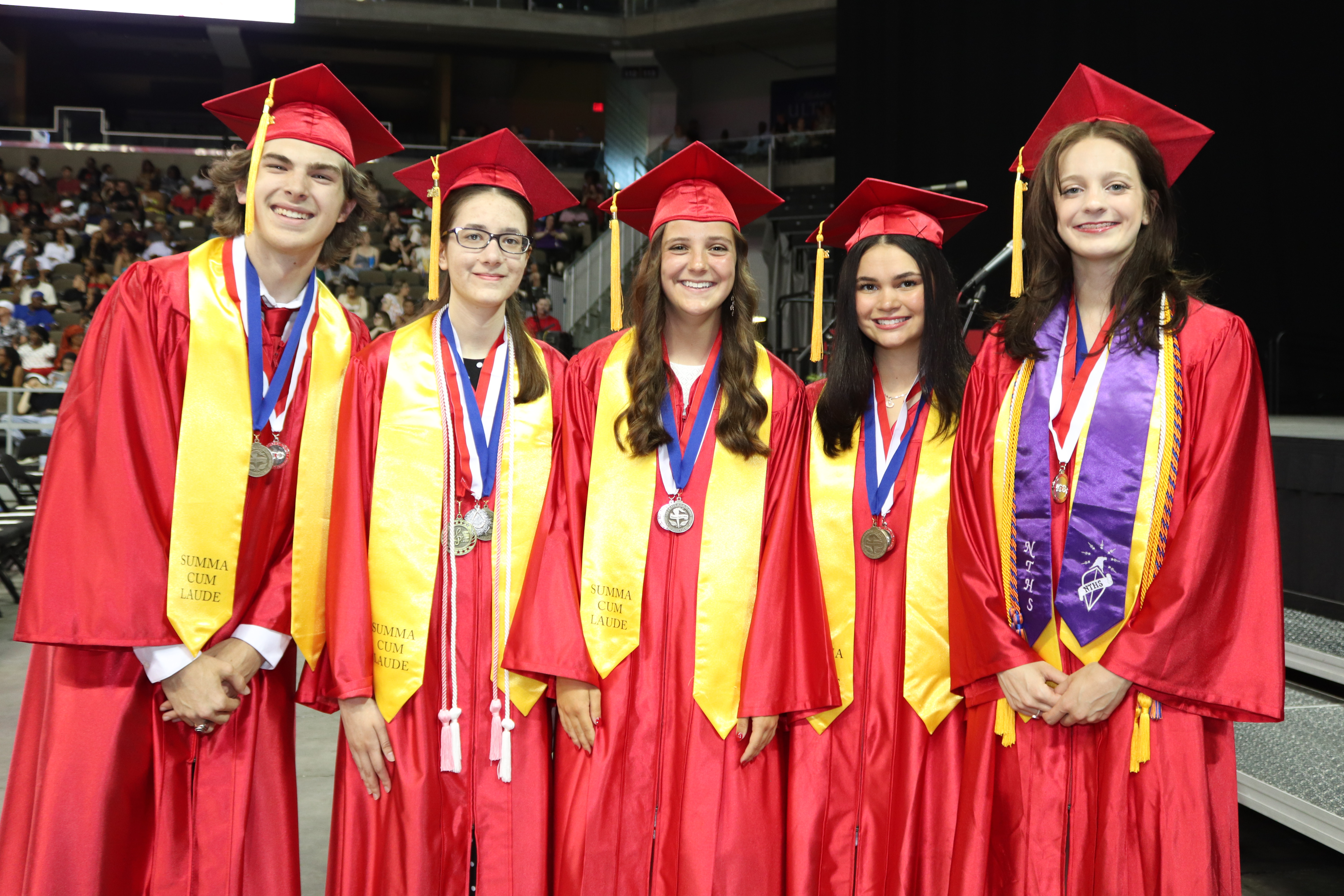 Five Colerain High School Graduates at graduation in their caps and gowns who have their gold stoles on.