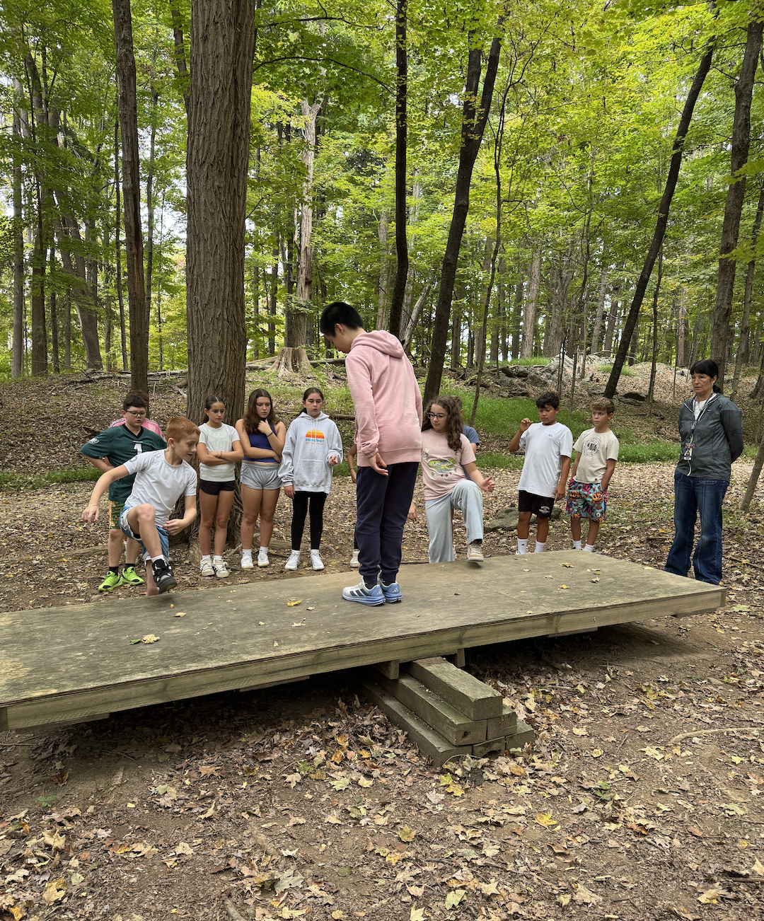 Pictures of students working together in the woods on obstacles