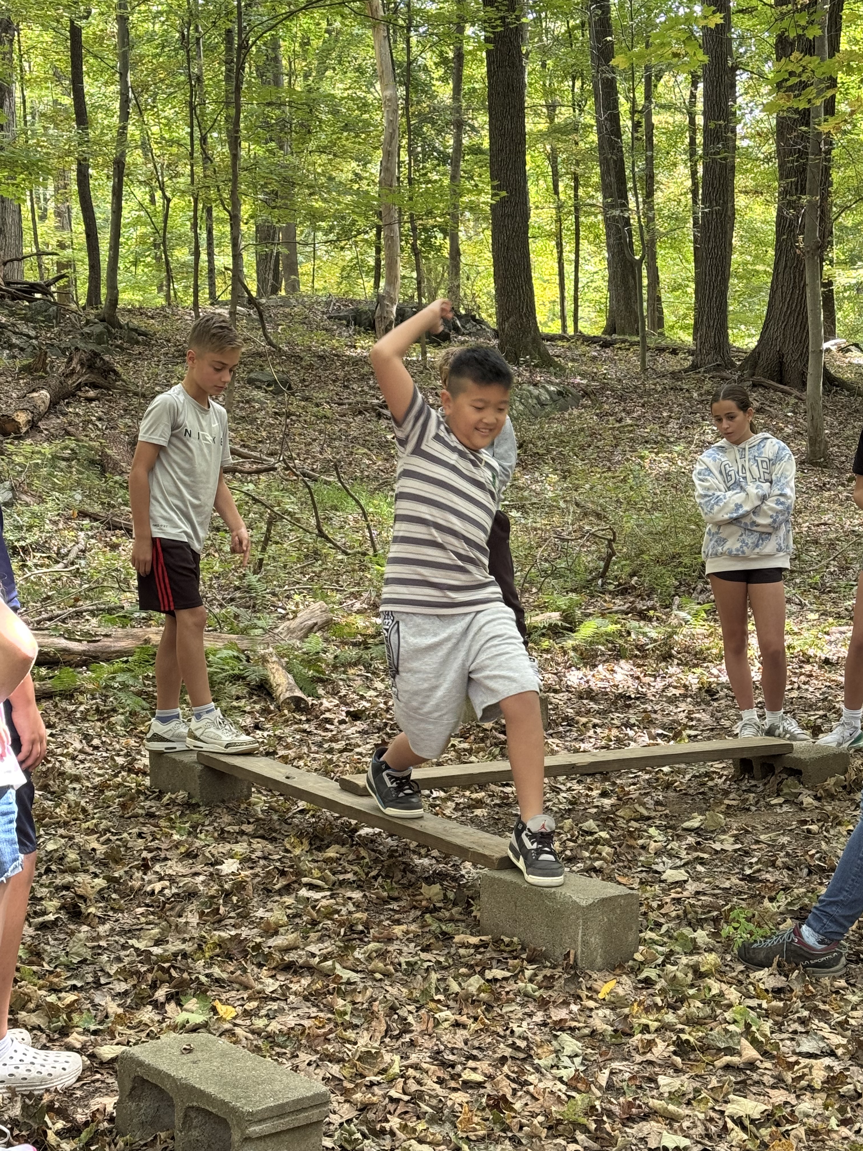 Pictures of students working together in the woods on obstacles