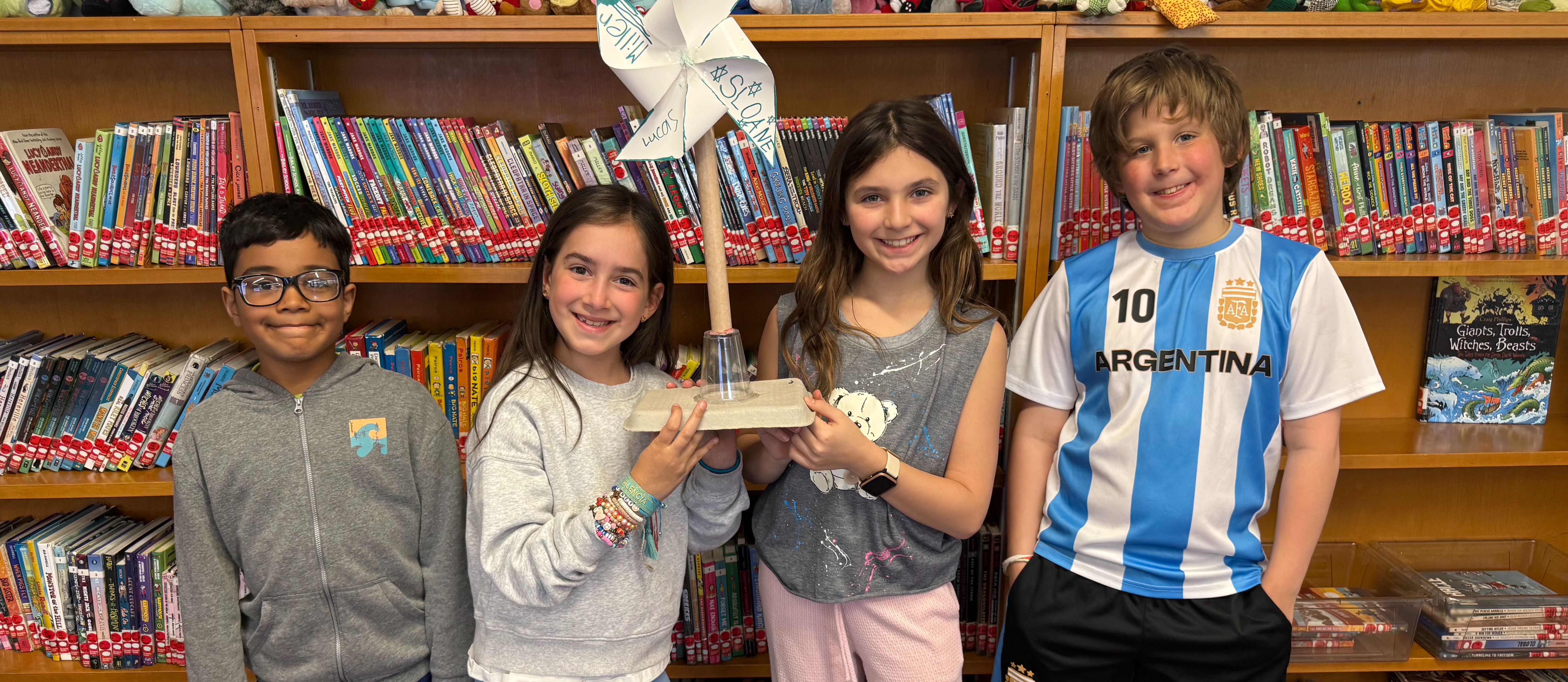 students holding paper windmills