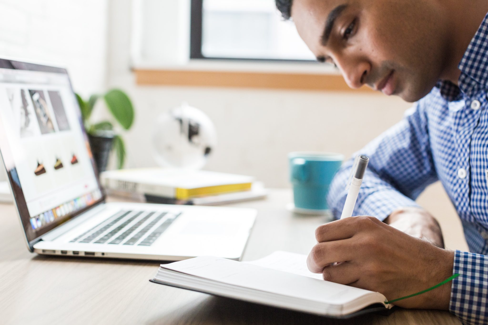 A man writing in a notebook at a desk.