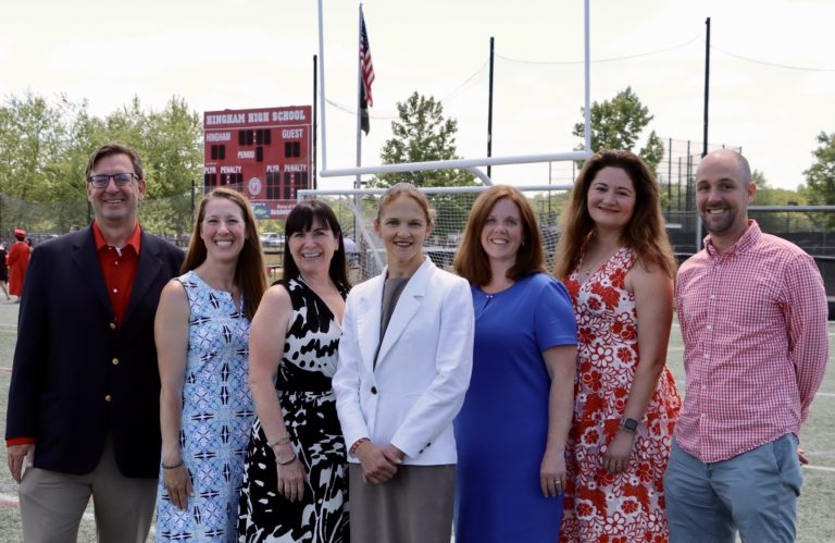 A diverse group of individuals standing on a soccer field, ready to engage in a game of soccer.