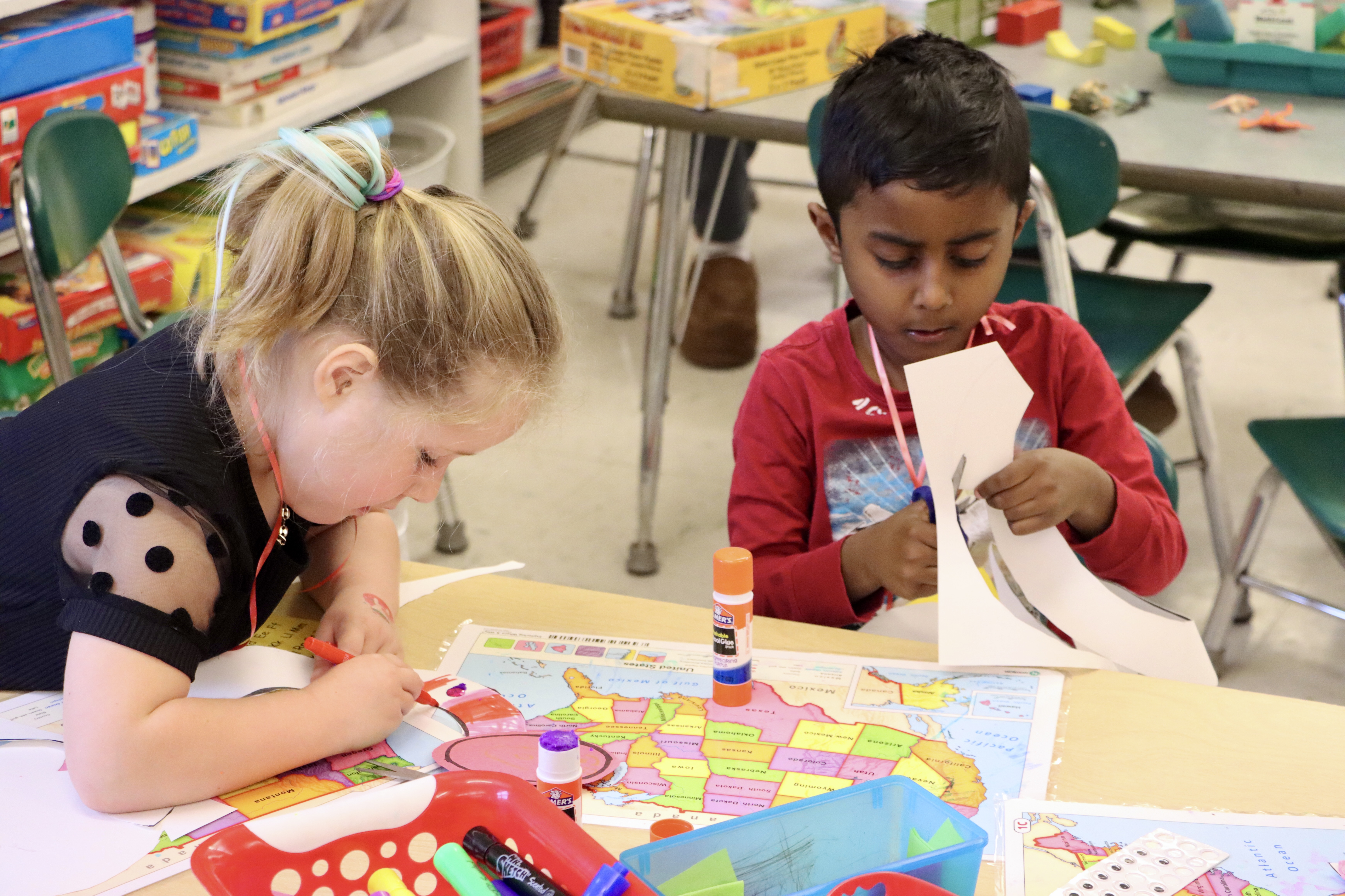 two kids making crafts with scissors and glue.