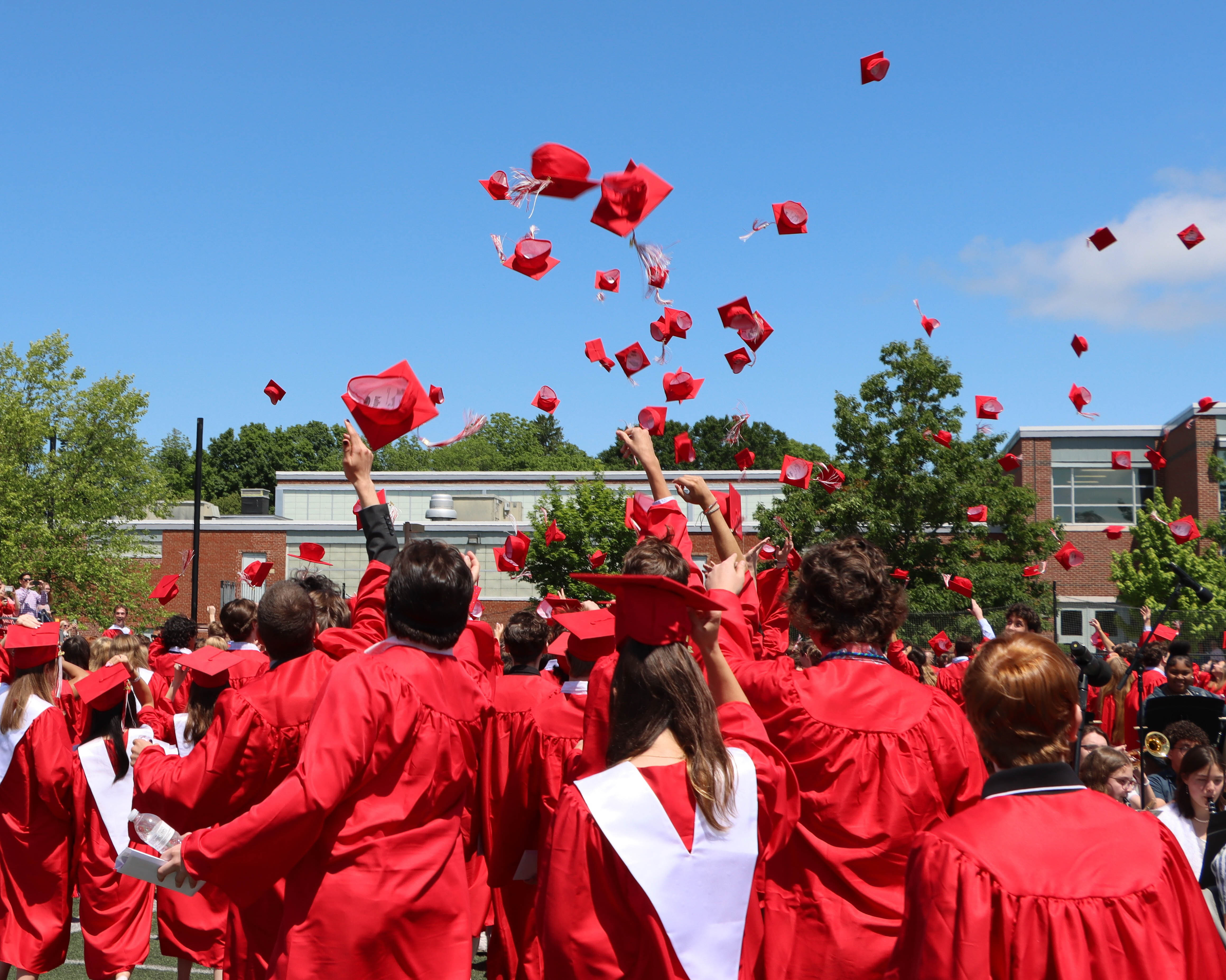 graduates throwing caps on a sunny blue sky day.