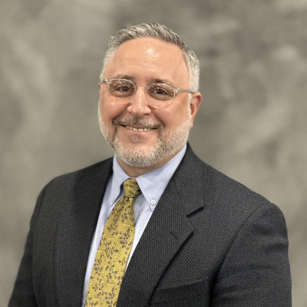 Headshot of Dr. Sal Minolfo, wearing a suit with a yellow tie.