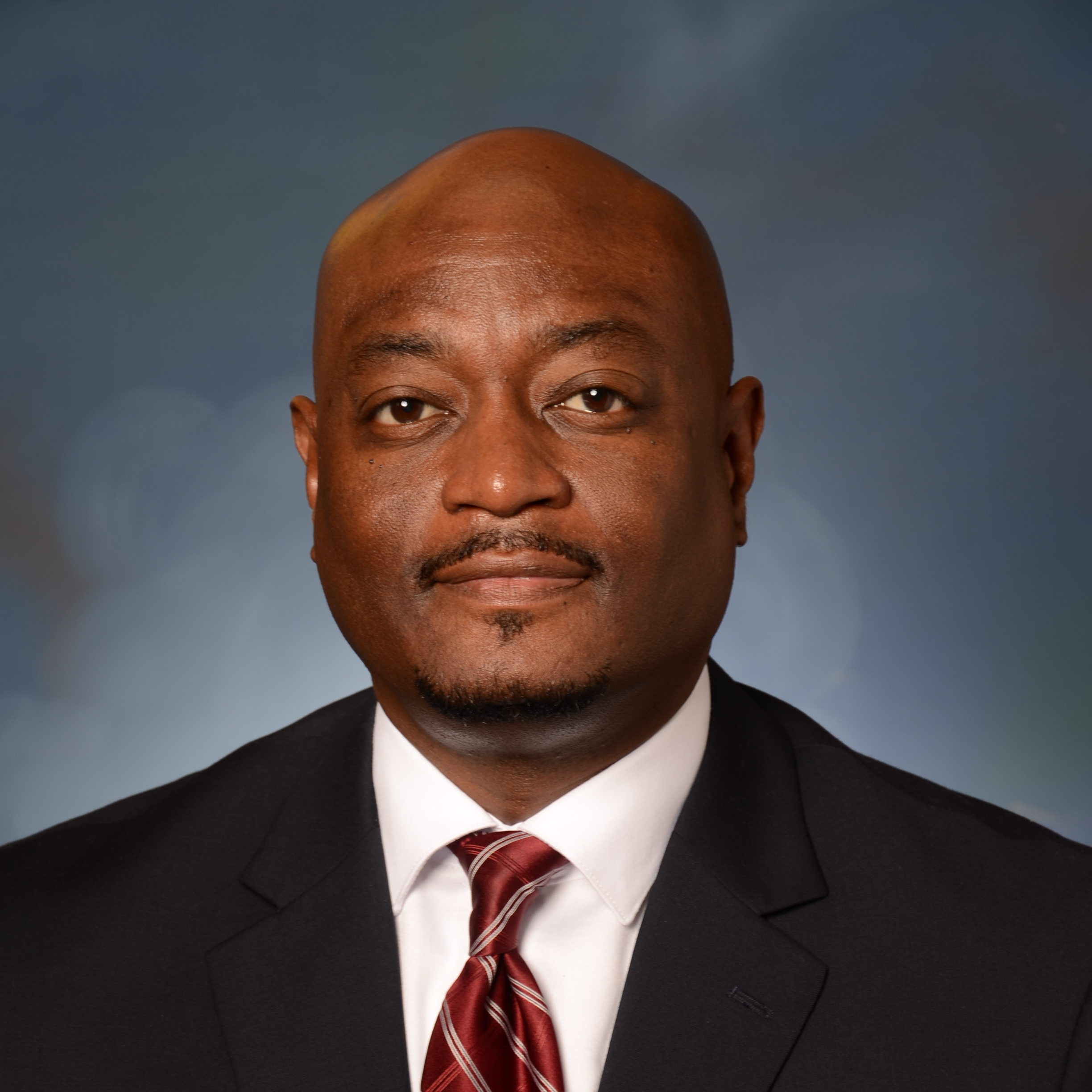 Headshot of Dr. Corey Murphy, wearing a suit with a red tie.