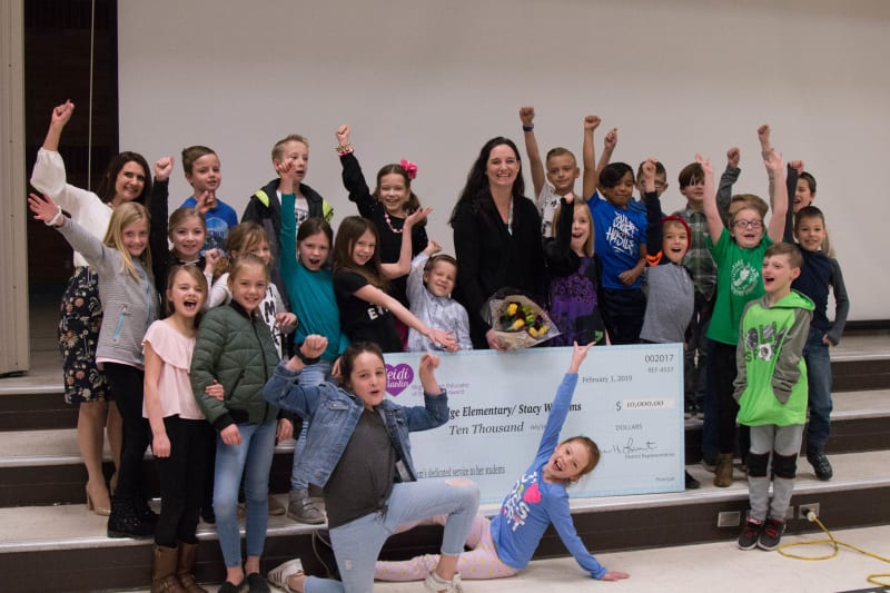 group of students and a teacher cheering for receiving a donation check