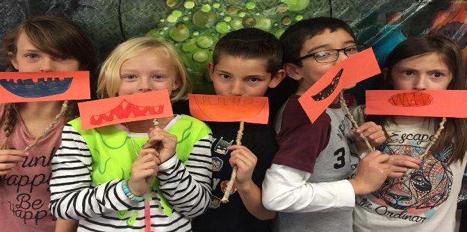 3rd grade students holding drawings of mouths up to their faces