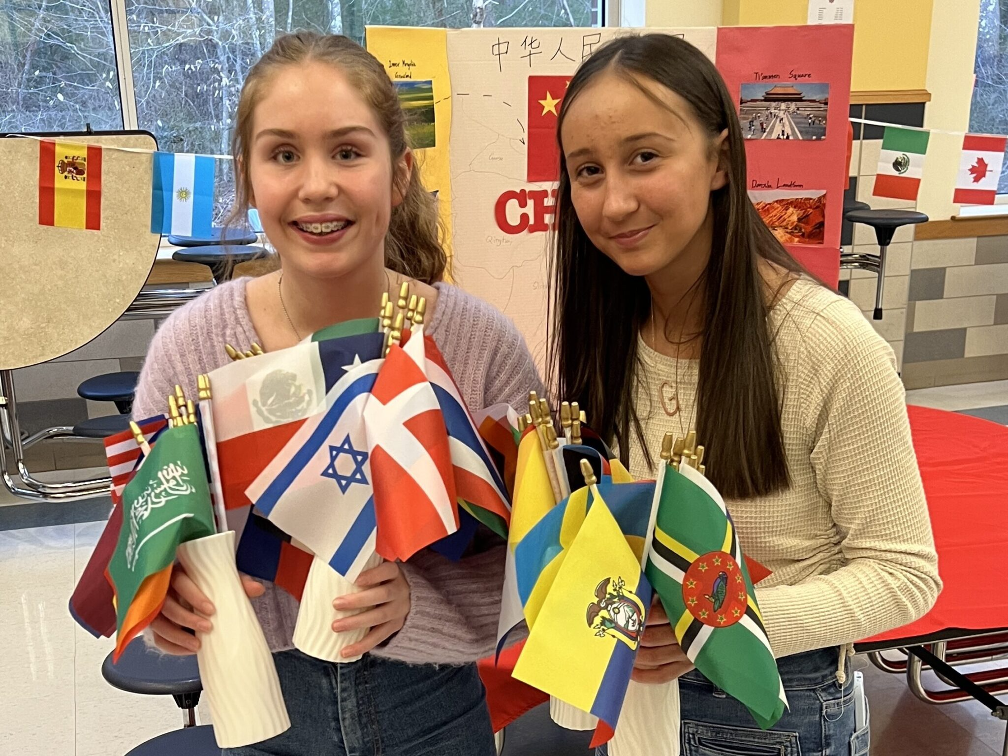 Two girls proudly holding up flags in their hands, showing their patriotism and unity.