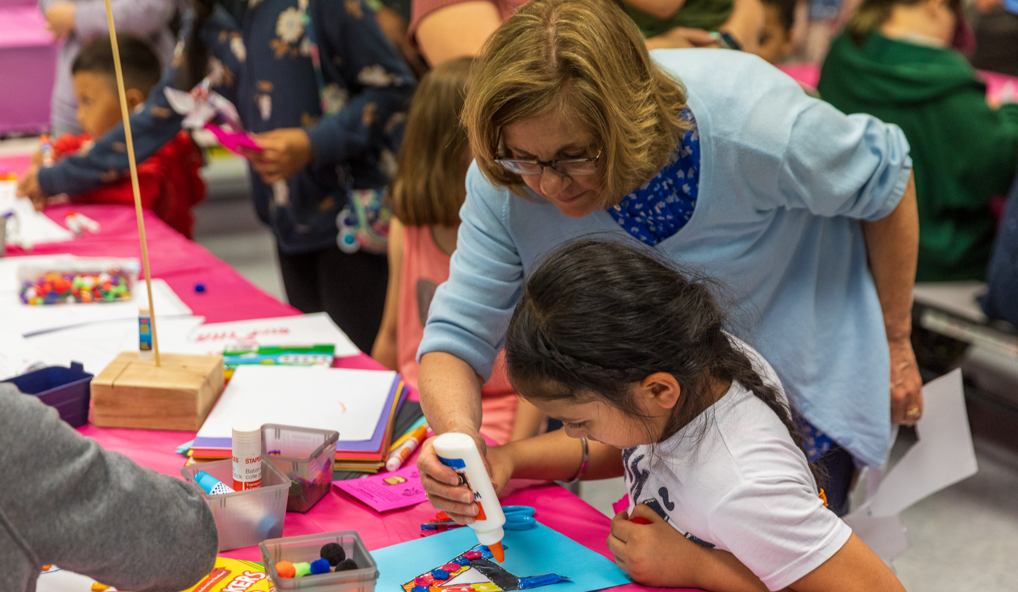 Teacher helping girl with a craft