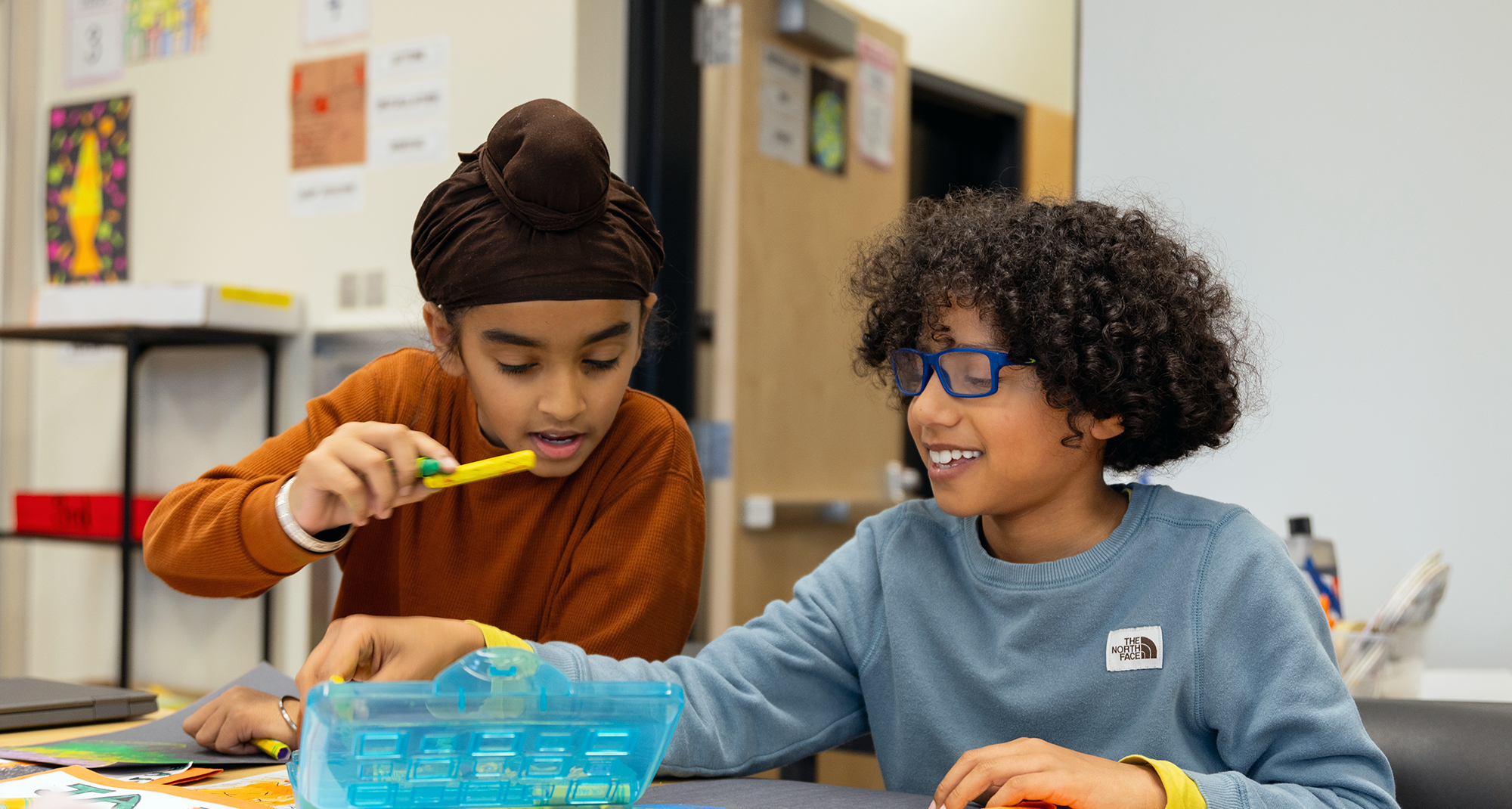 Two children collaborate on a craft project, focused and engaged in their creative activity together