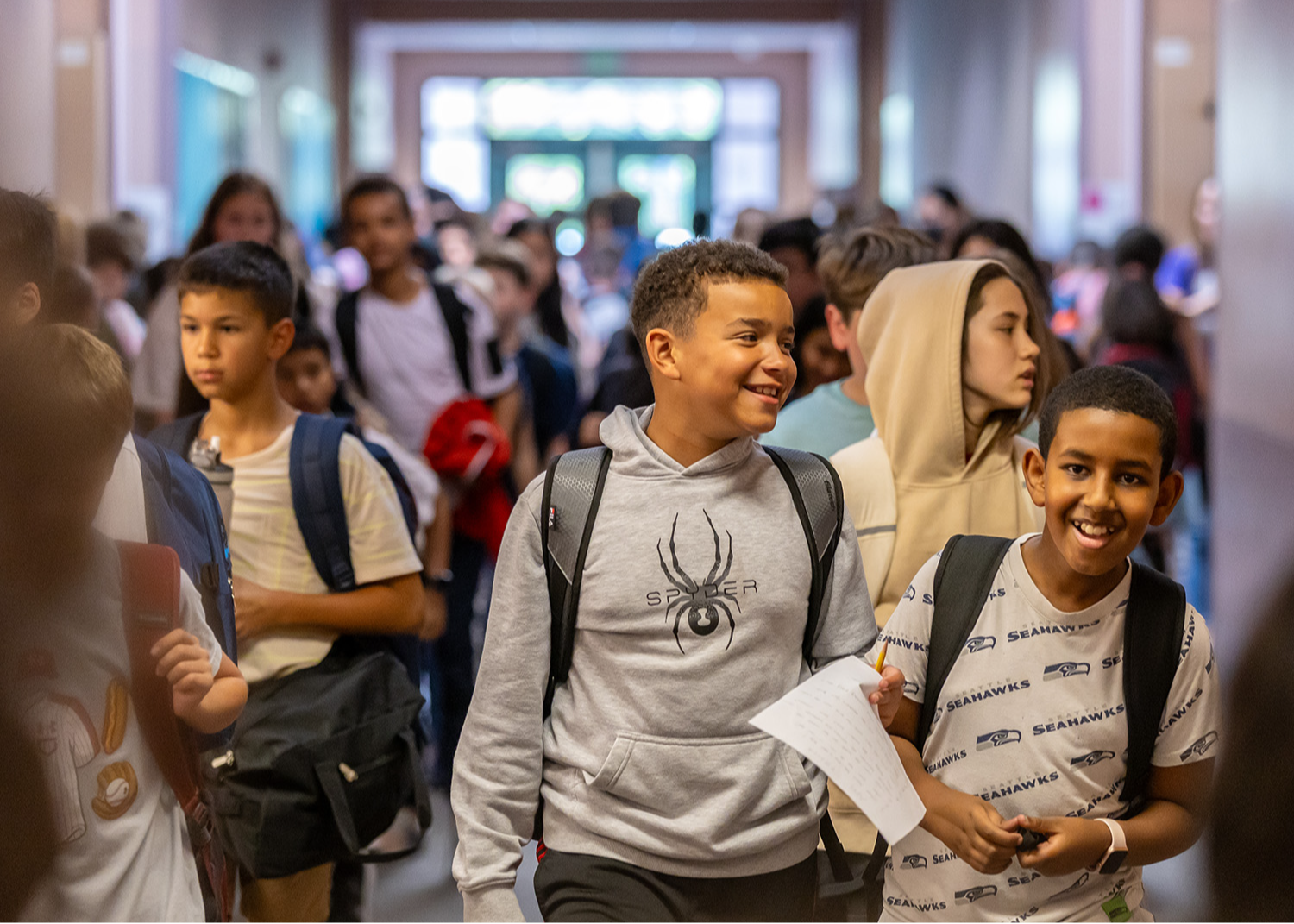 Students walking in a hallway smiling