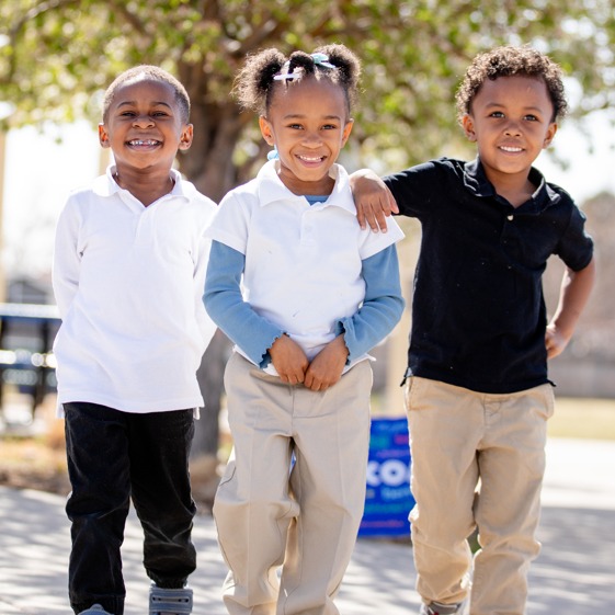 Three children posing together in front of a desk.