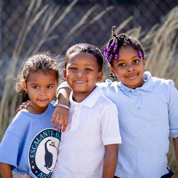 Three children posing together in front of a desk.