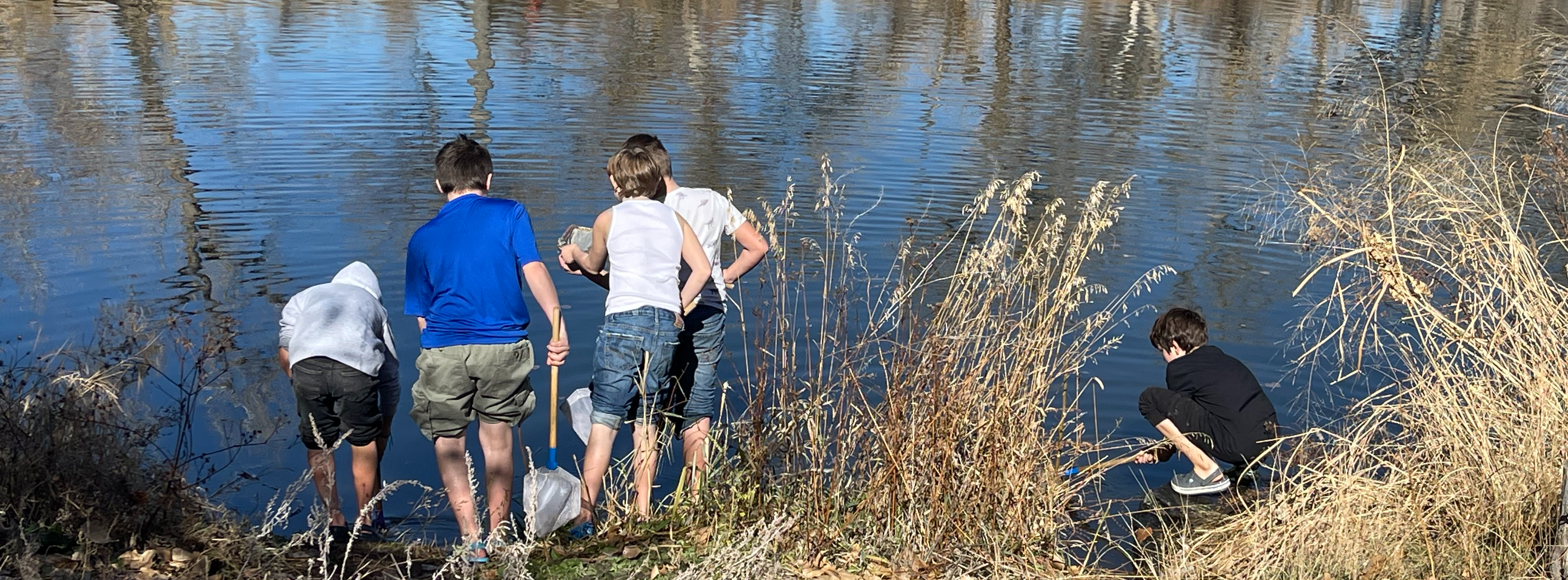 three students standing on the bank of a river