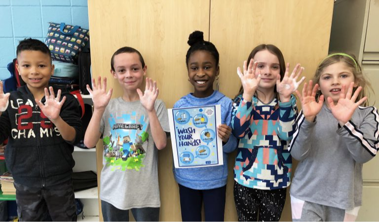 Five elementary students showing their hands