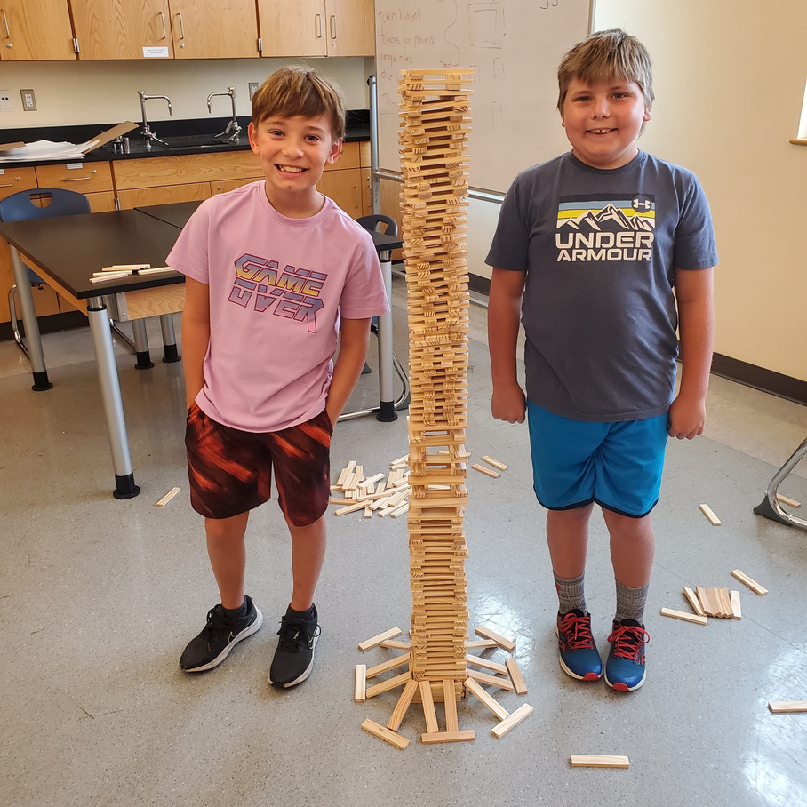 Two young boys proudly building a Jenga tower.