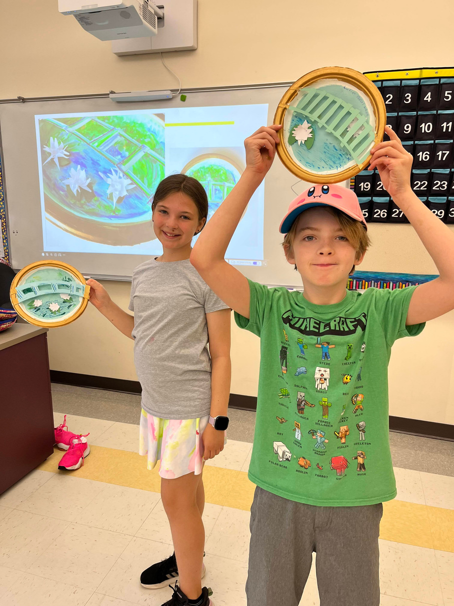 Two children proudly displaying their artwork.