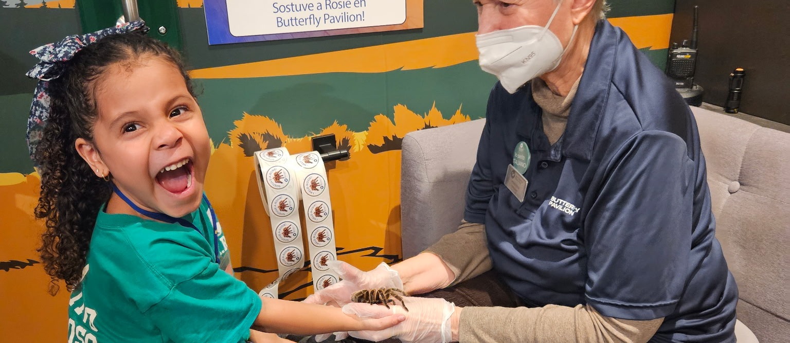 student smiling with tarantula