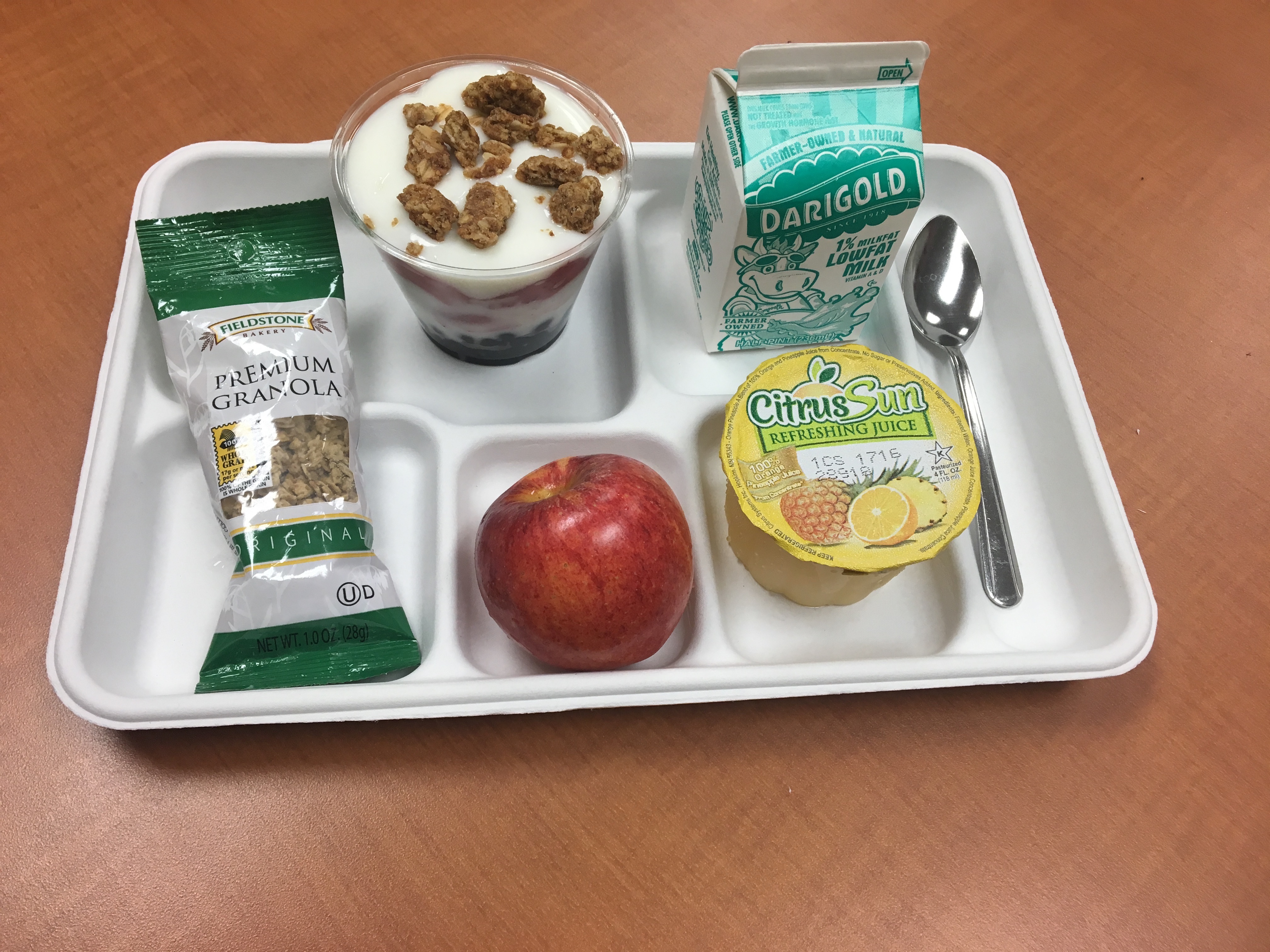 breakfast food including milk, a parfait and apple on a tray