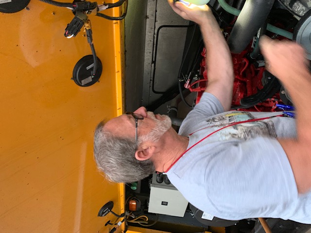 person working on a bus undercarriage 