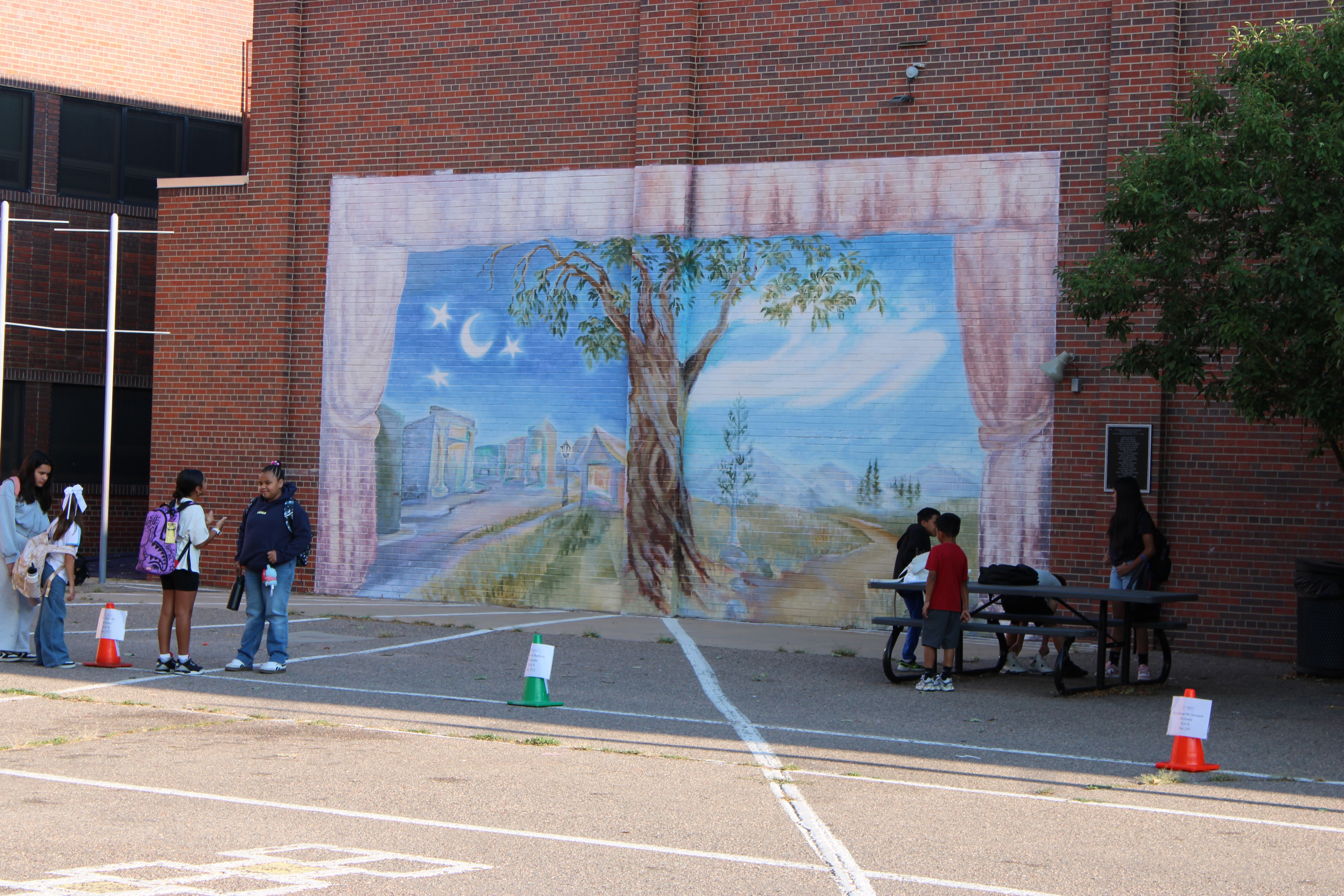 A mural of a tree painted outside on a wall on the playground