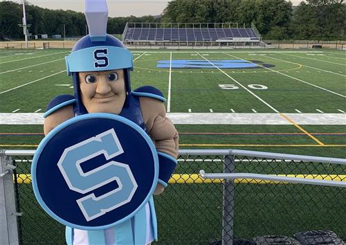 A photo of a man in a mascot costume in front of a football field