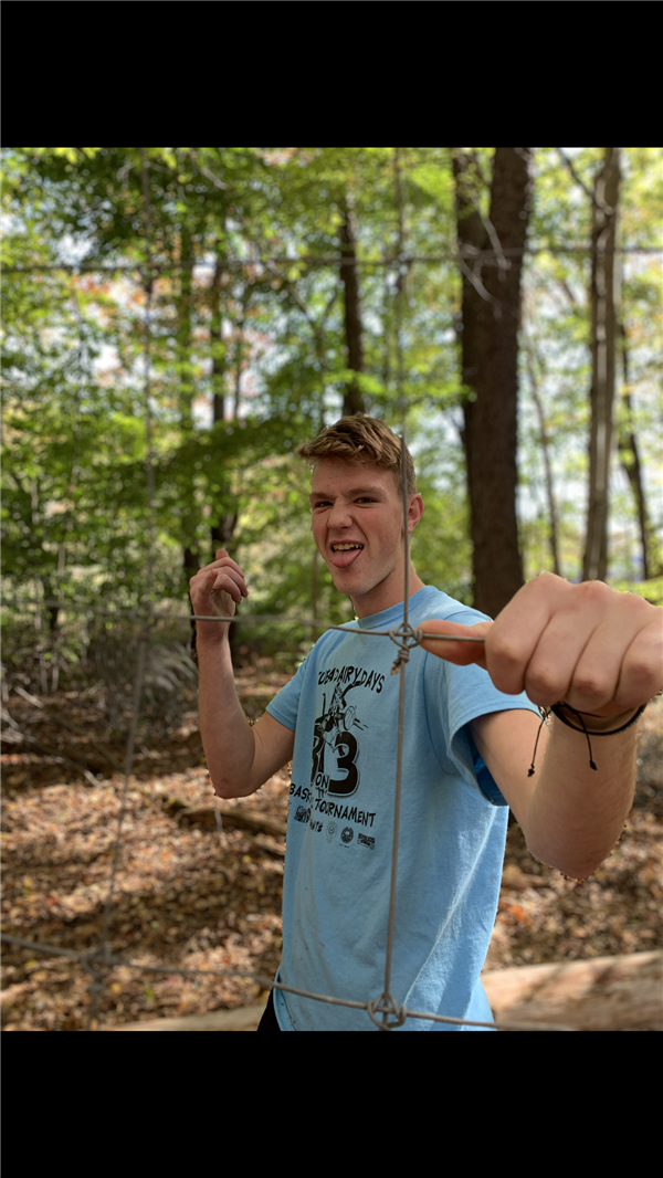 A boy wearing a blue shirt posing for a picture behind a big net.