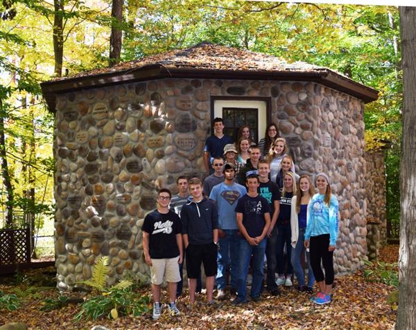 People posing for a picture in front of a small cabin.